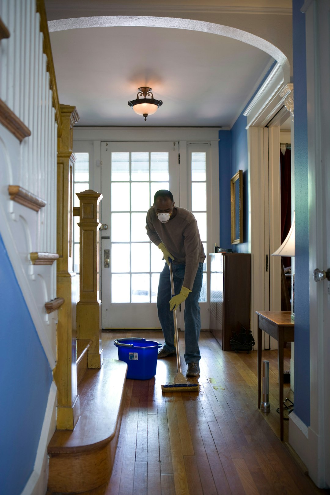 This African-American man was in the middle of damp-mopping the entryway of his home. By doing so, airborne particles such as dust and pollen could be cleared from inside the house, helping lessen the harmful impact these substances can have on the respiratory health of his family. These irritants may sometimes lead to sinus infections and asthma.